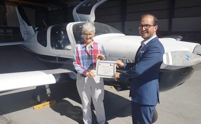 El Presidente Ejecutivo del IMAS, Juan Luis Bermúdez, hace entrega de la avioneta a la señora osa Ruiz, directora del SIFAIS. La avioneta se encuentra parqueada al fondo.