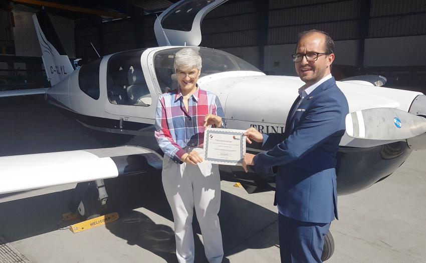 El  Presidente Ejecutivo del IMAS, Juan Luis Bermúdez, hace entrega de la avioneta a la señora osa Ruiz, directora del SIFAIS. La avioneta se encuentra parqueada al fondo.