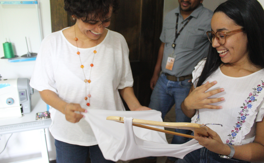 En la foto Hillary Jiménez, beneficiaria del subsidio Emprendimiento Productivo Indivudual mostrando artículos confeccionados a la Presidenta Ejecutiva del IMAS Yorleny Marchena León