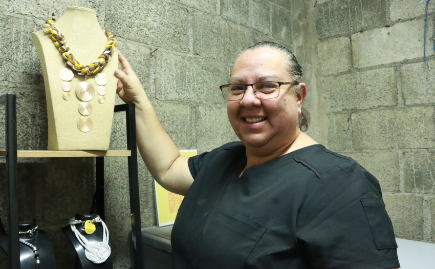 Sofía Naranjo, emprendedora beneficiaria del IMAS, sonríe hacia al frente y posa con productos de joyería artesanal que diseña. 