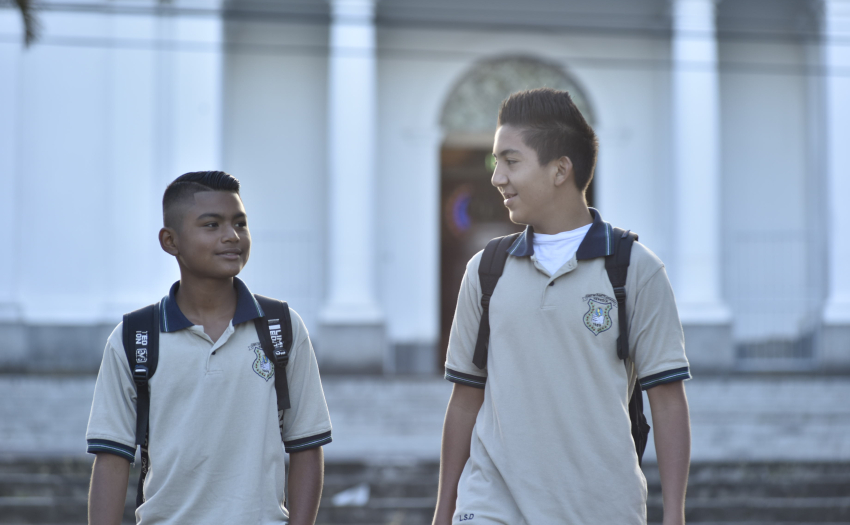 Dos estudiantes de colegio caminan por la calle. 
