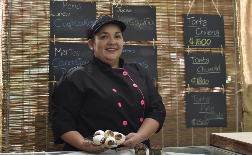 Beneficiaria del IMAS posa en panadería. En sus manos tiene un plato con repostería. 